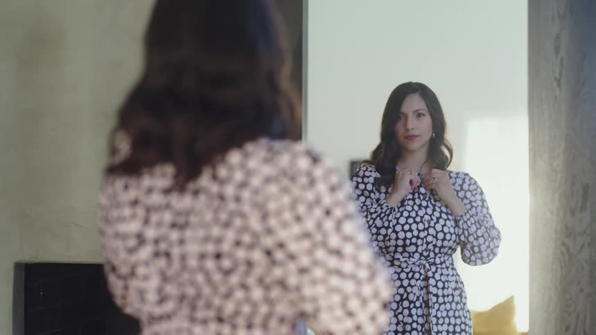 A woman in a room standing in front of a mirror with a wall in the background