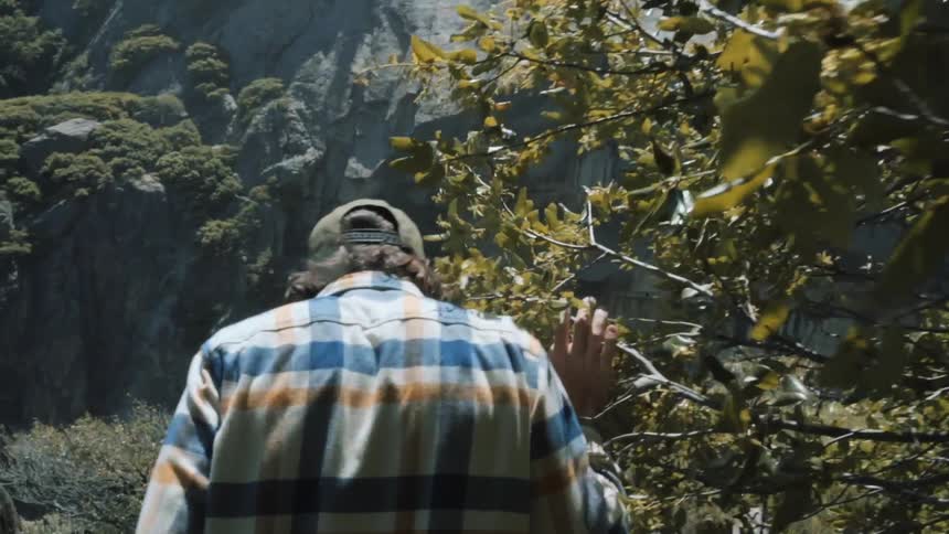 A man is hiking near the foot of a mountain