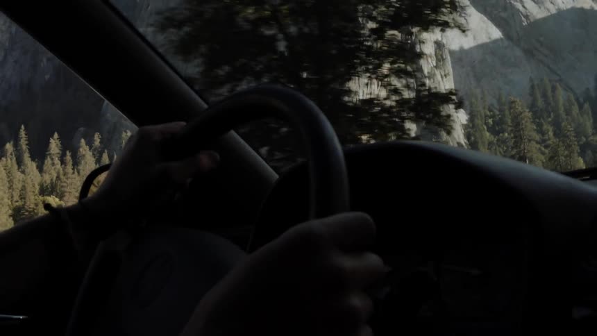 A car is driving past a tall mountain