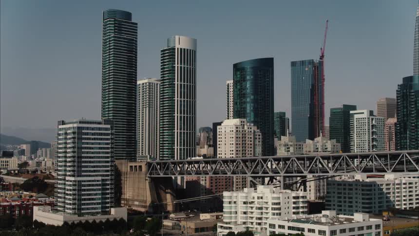 A city skyline with a bridge with vehicles buildings and skyscrapers with the sky and clouds in the background