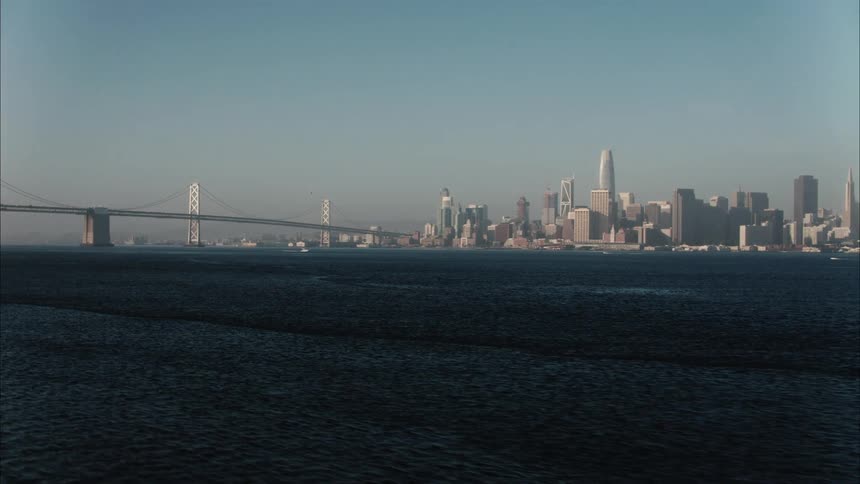 View of suspension bridge and city skyline against blue sky