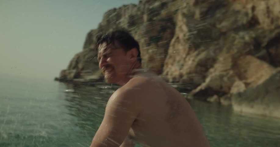 Young happy couple playing with water on the shallow beach near a cliff