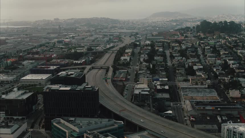 An aerial view of cars driving down a road past office buildings
