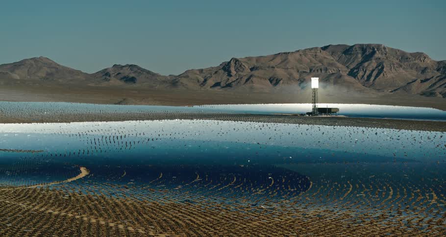 A landscape with solar reflectors a mountain range the sky and clouds in the background