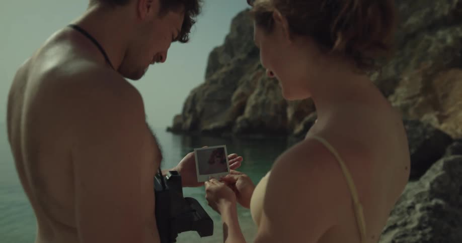 A couple shake a polaroid photo and kiss