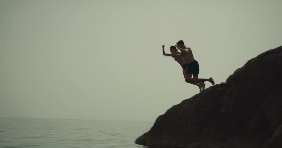 A man and woman jump into the water from the cliff