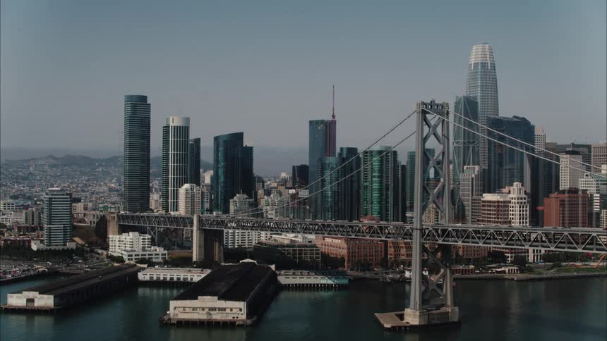 Aerial view of suspension bridge over river and high rise city buildings