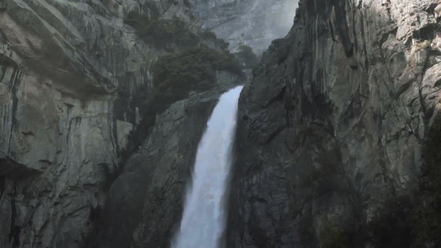 Waterfall tumbles over a high cliff while it is raining