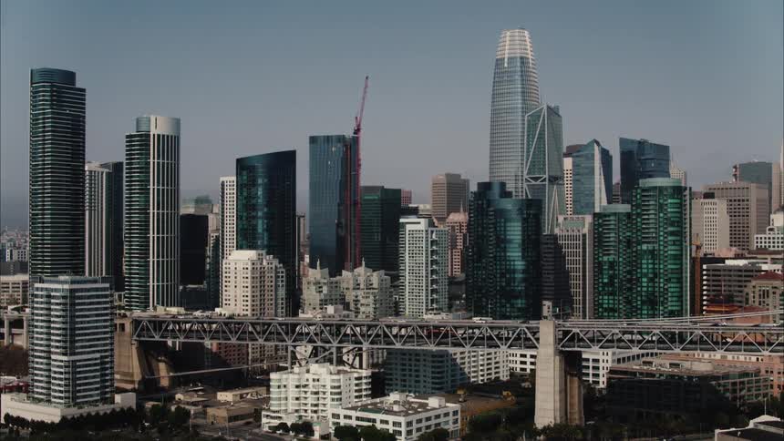 Traffic moves across a bridge going into a city with tall modern buildings along the skyline