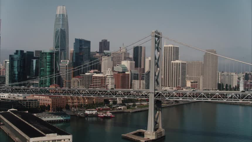 Traffic drives over a river on a bridge leading in and out of downtown