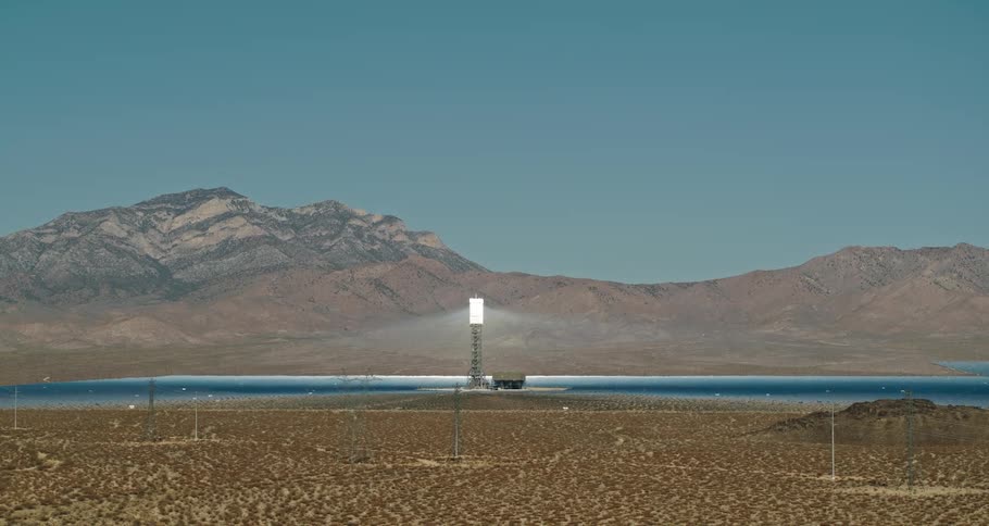 A landscape with utility poles with a mountain range the sky and clouds in the background