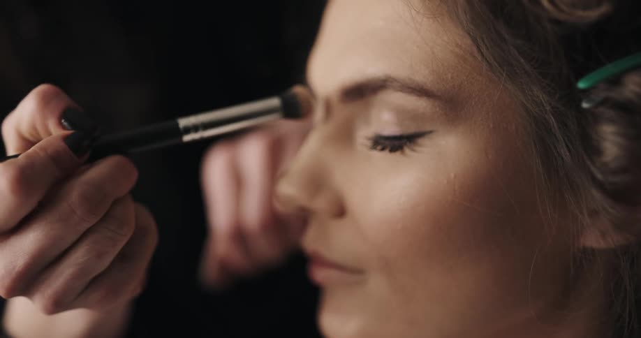 Makeup artist applying makeup on the nose of a woman
