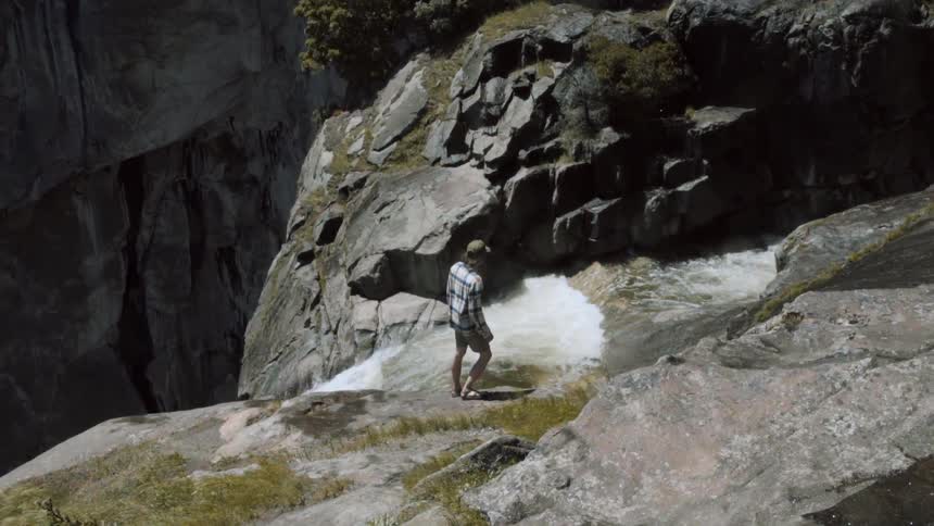 A man stands at the top of a waterfall