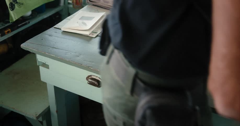 A man puts on glasses as he stands up to walk away with a radio