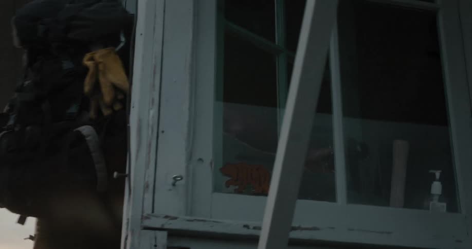 A man with a backpack on unlocks a door and enters a building
