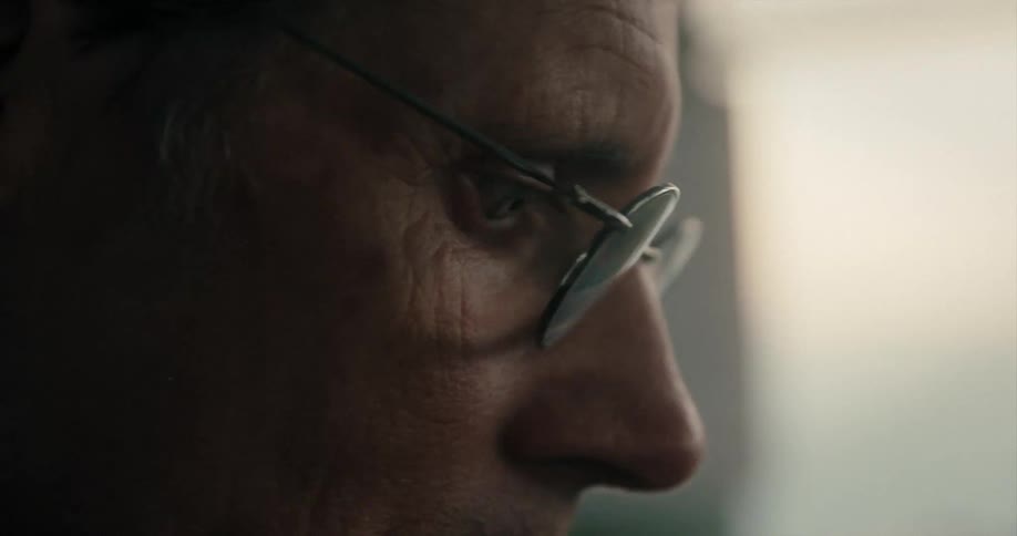 A man in a room with glasses with a wall in the background