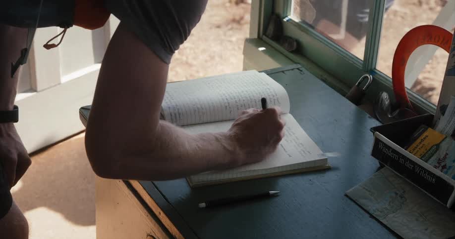 Man with shorts and t shirt writes on notebook next to door