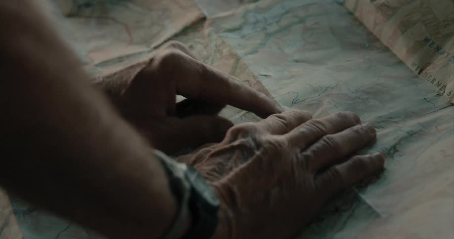 An elderly person has their hands on a large unfolded map