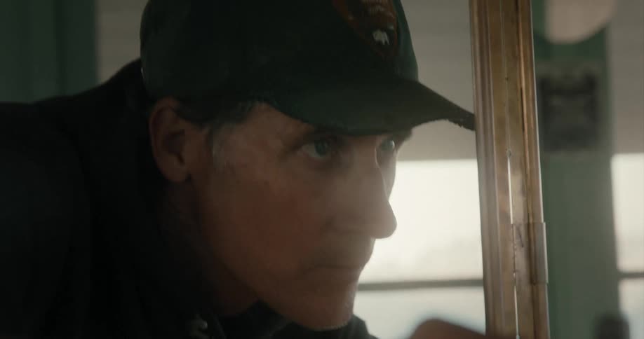 Man wearing a baseball cap squinting while looking closely at something