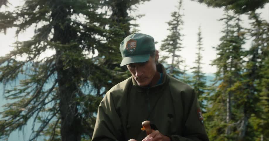 A man hiking in a forest pops some food in to his mouth and chews