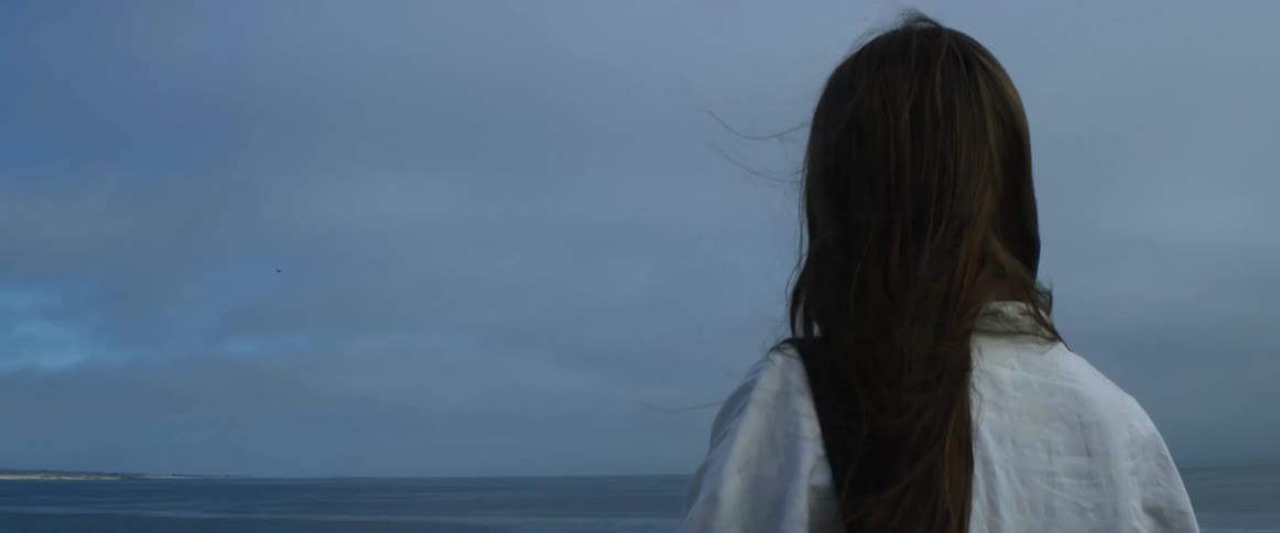 A woman with a tablet and a stylus with the ocean sky and clouds in the background
