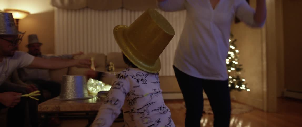 A child and family are dancing and playing in a living room