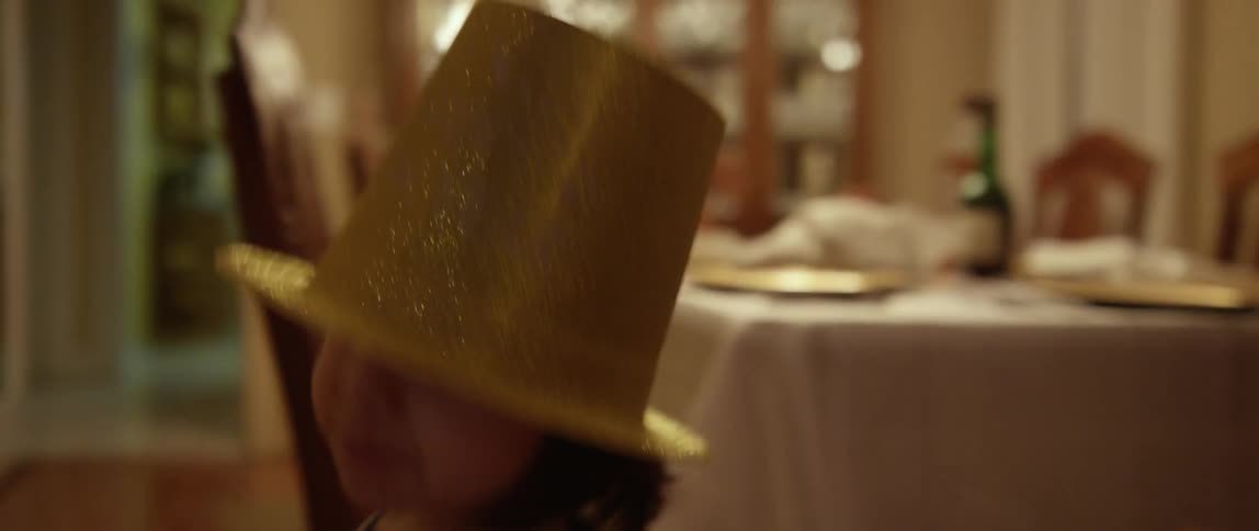A child is walking back and forth wearing a gold hat and waving a toy