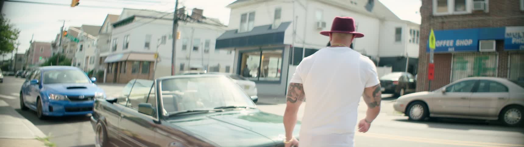 A tattooed man in a pink hat walks to his car
