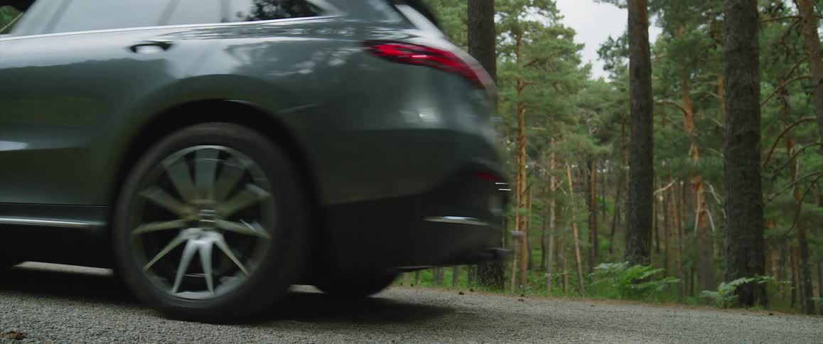 A crossover vehicle drives past a forest