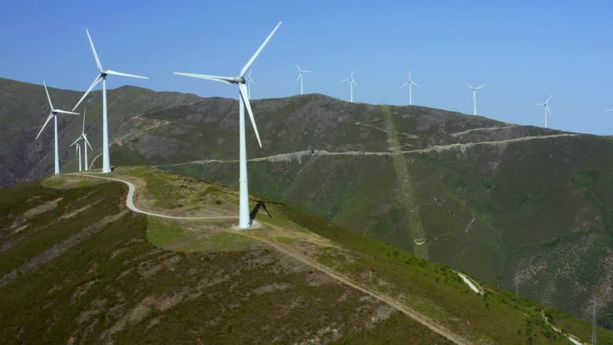 Wind turbines spin on the tops of steep hills in the countryside