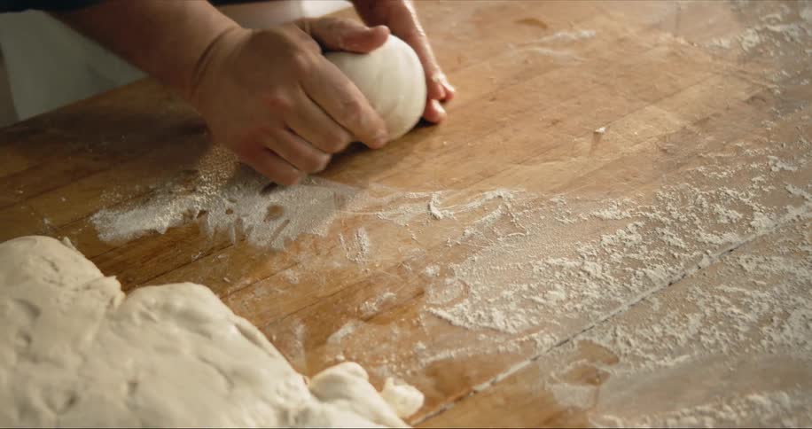 A baker rolls balls of dough on the counter