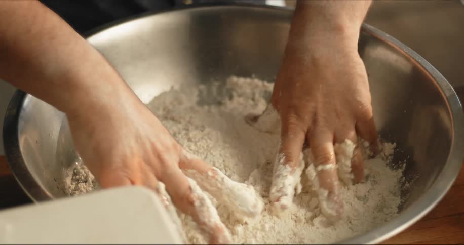 Man kneads dough in silver bowl