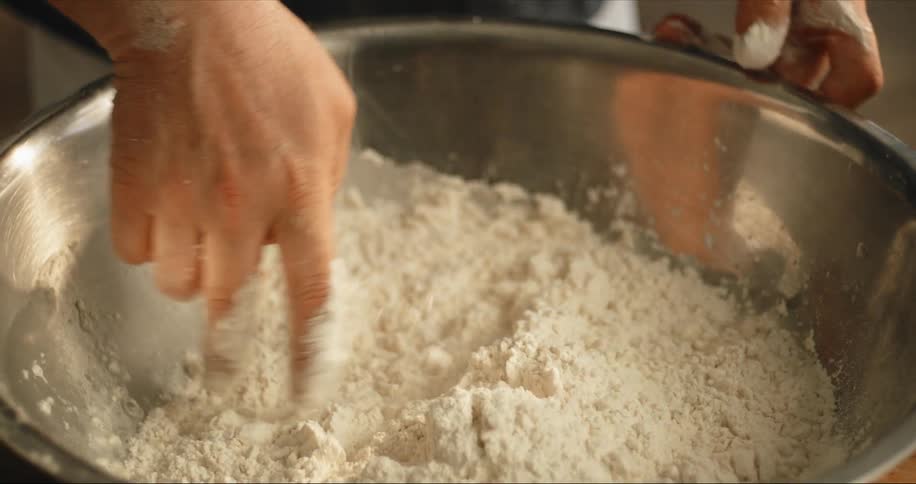 Mans hands knead dough in silver bowl