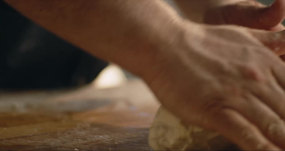 A cook is rolling a ball of dough