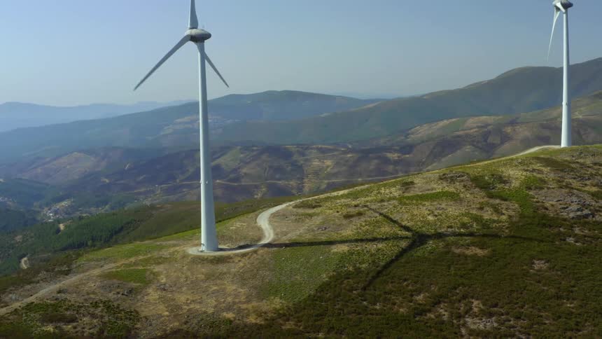 An aerial view of windmills at the top of a hill