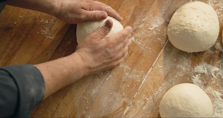 A man rolls a ball of dough