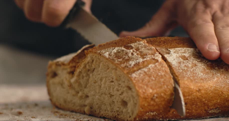 A person cutting bread on a table with a knife