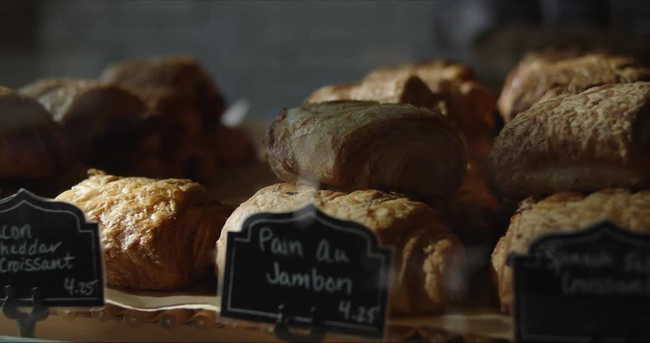 Labels identify different types of filled croissants sitting in piles in bakery display case