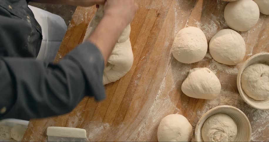 Man kneading bread dough over a table in the kitchen