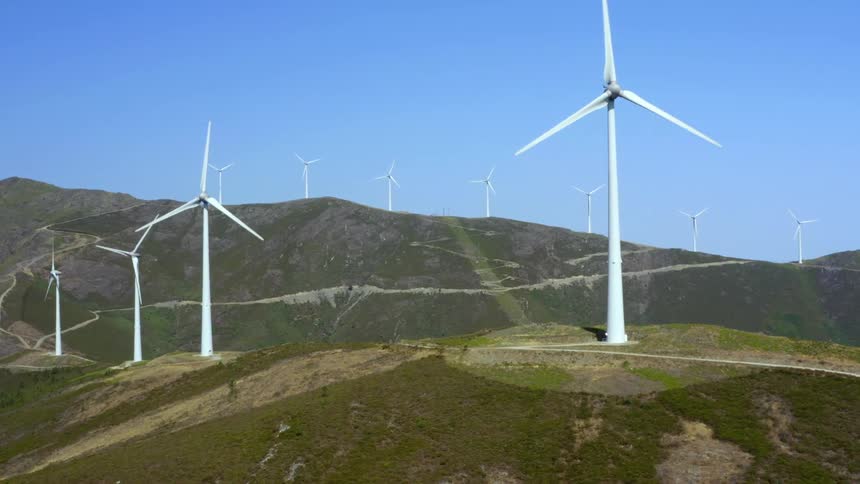 Aerial view of wind turbines spinning on the mountains under the blue sky