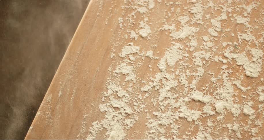 Chef spreading flour with his hand over a wooden table