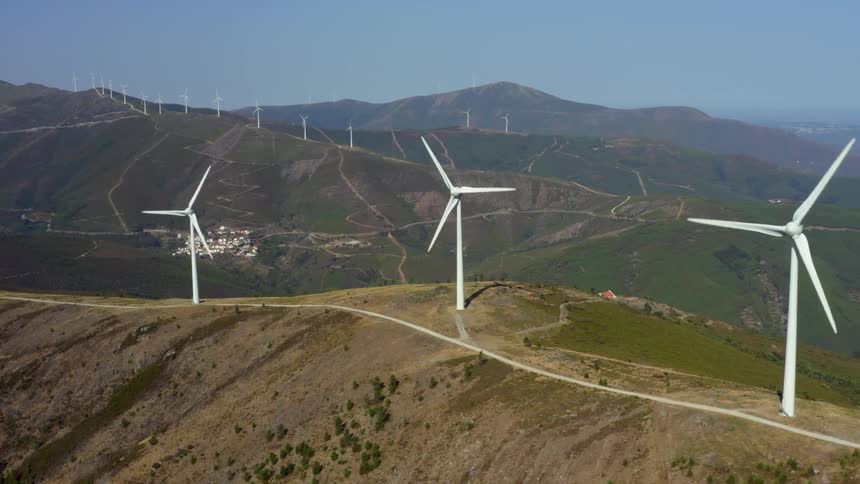 Wind turbines spin on the top of tall hills in the countryside