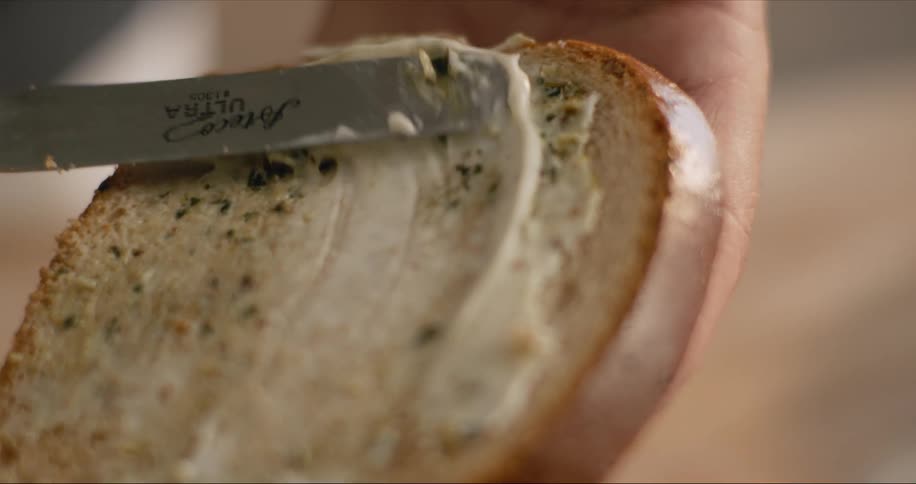 Person spreading cream over a toast with a knife