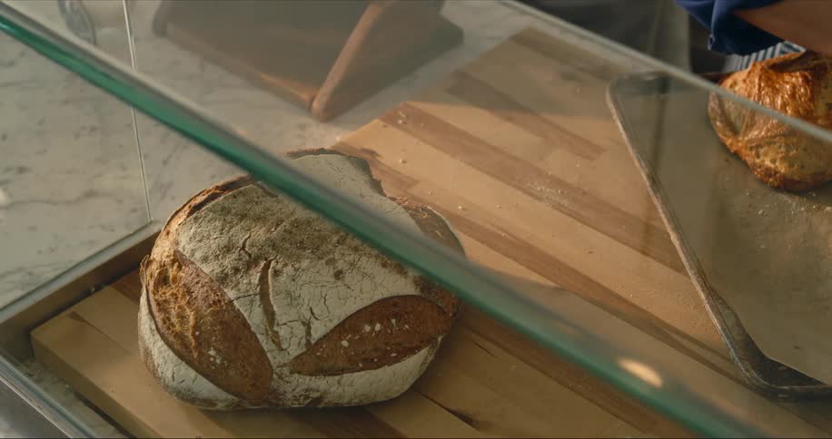 A woman sets loaves of bread out in a display case