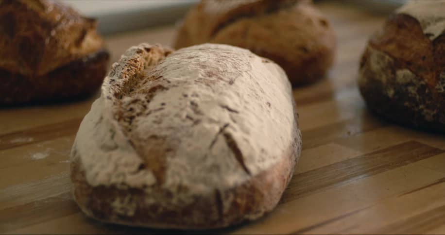 Freshly baked loaves of bread sit on a wooden countertop
