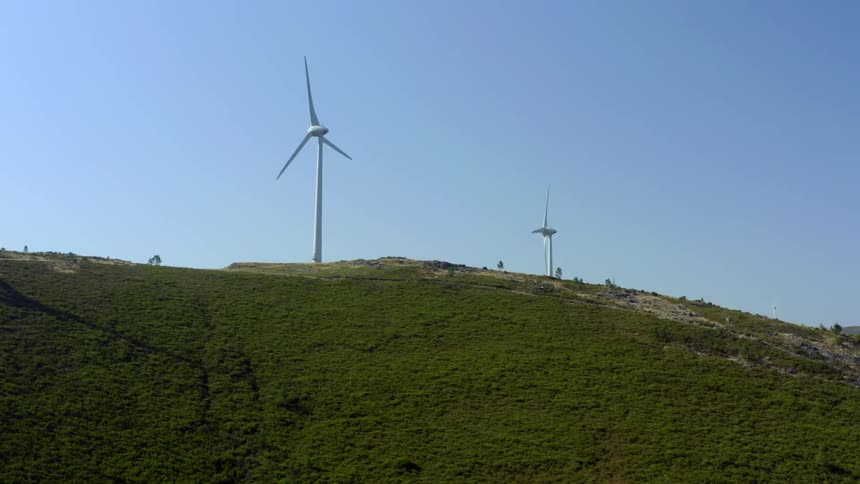 Hills with trees and wind turbines with the sky and clouds in the background