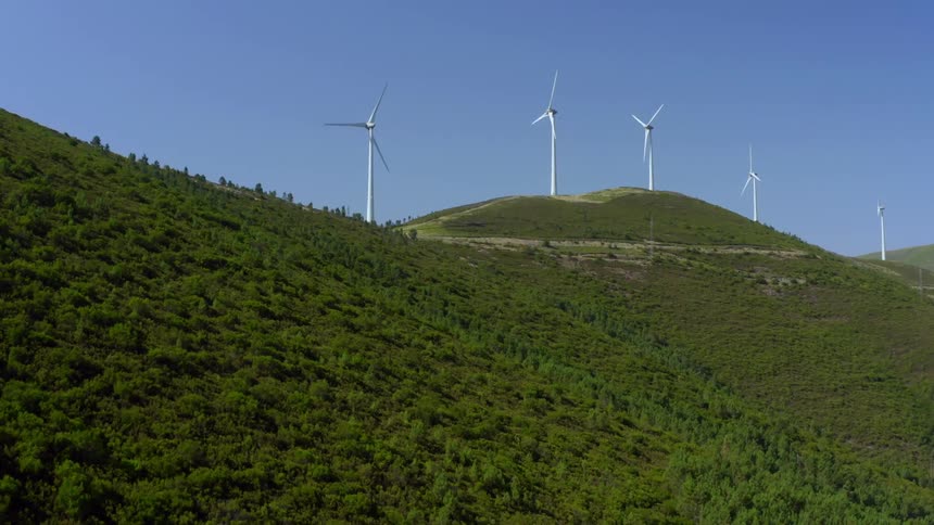 Hills with trees and wind turbines with the sky and clouds in the background