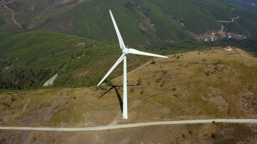 Aerial view of wind turbine on wind farm with mountains