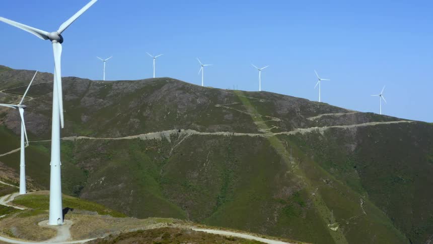 Wind turbines dotted across the landscape spin in the wind