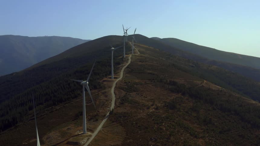 Aerial view of wind turbines on wind farm next to road on mountain